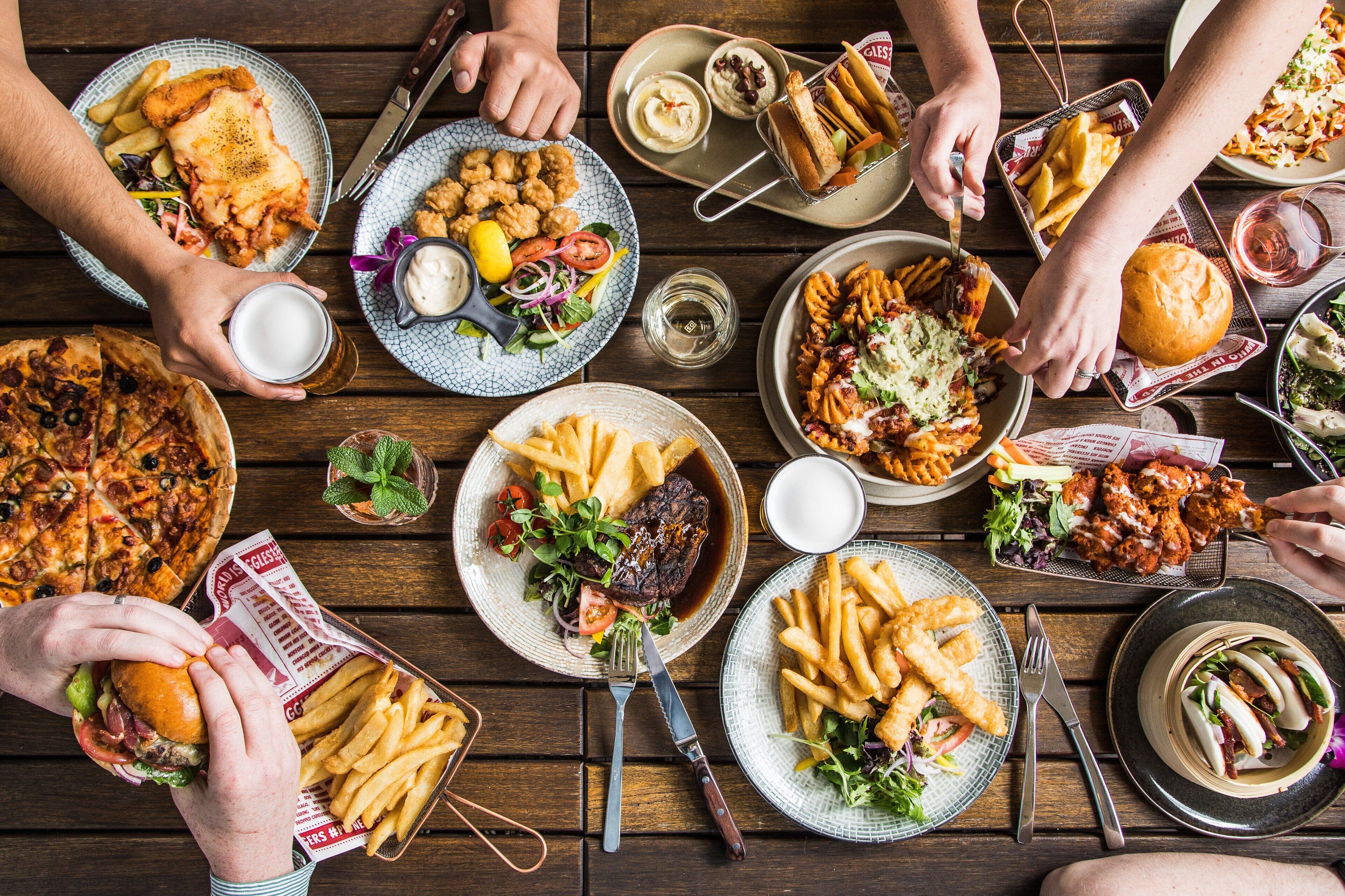 A table with various dishes including pizza, fries, and sandwiches.