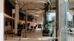 Un vestíbulo amplio con candelabros modernos, una recepción y plantas en macetas.