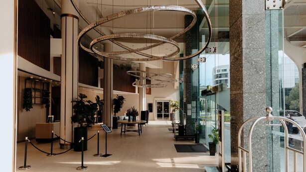 Een ruime lobby met moderne kroonluchters, een receptiebalie en potplanten.