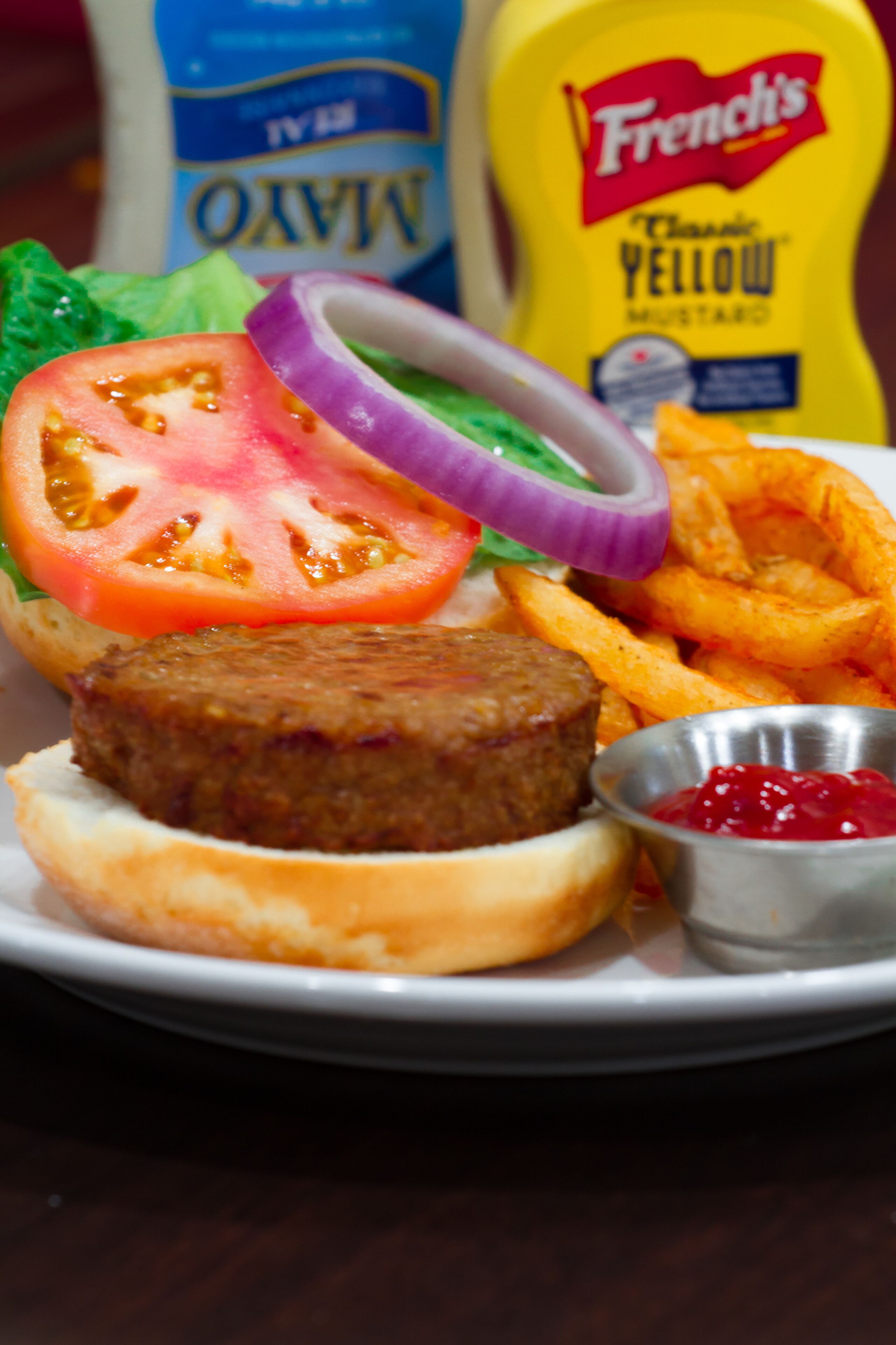Un plato con una hamburguesa, papas fritas y una porción de kétchup.
