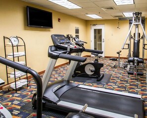 A hotel fitness room with a treadmill, elliptical, and weight machines.