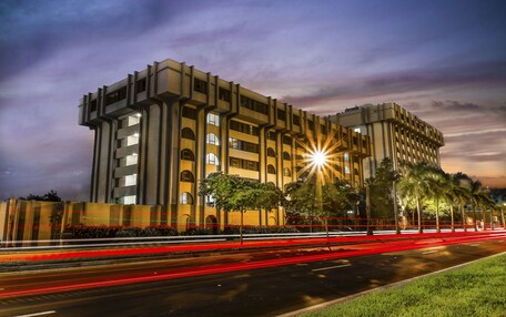 Un edificio moderno con fachada simétrica, numerosas ventanas y una entrada bien iluminada.