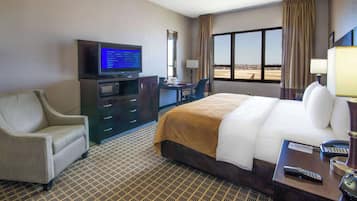Ein Hotelzimmer mit Bett, Schreibtisch, Fernseher, Sessel und Blick ins Freie.