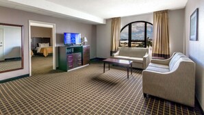 Hotellihuone, jossa on suuri ikkuna, televisio, sohva, sohvapöytä ja sänky, josta avautuu näkymä kaupungin ylle.
