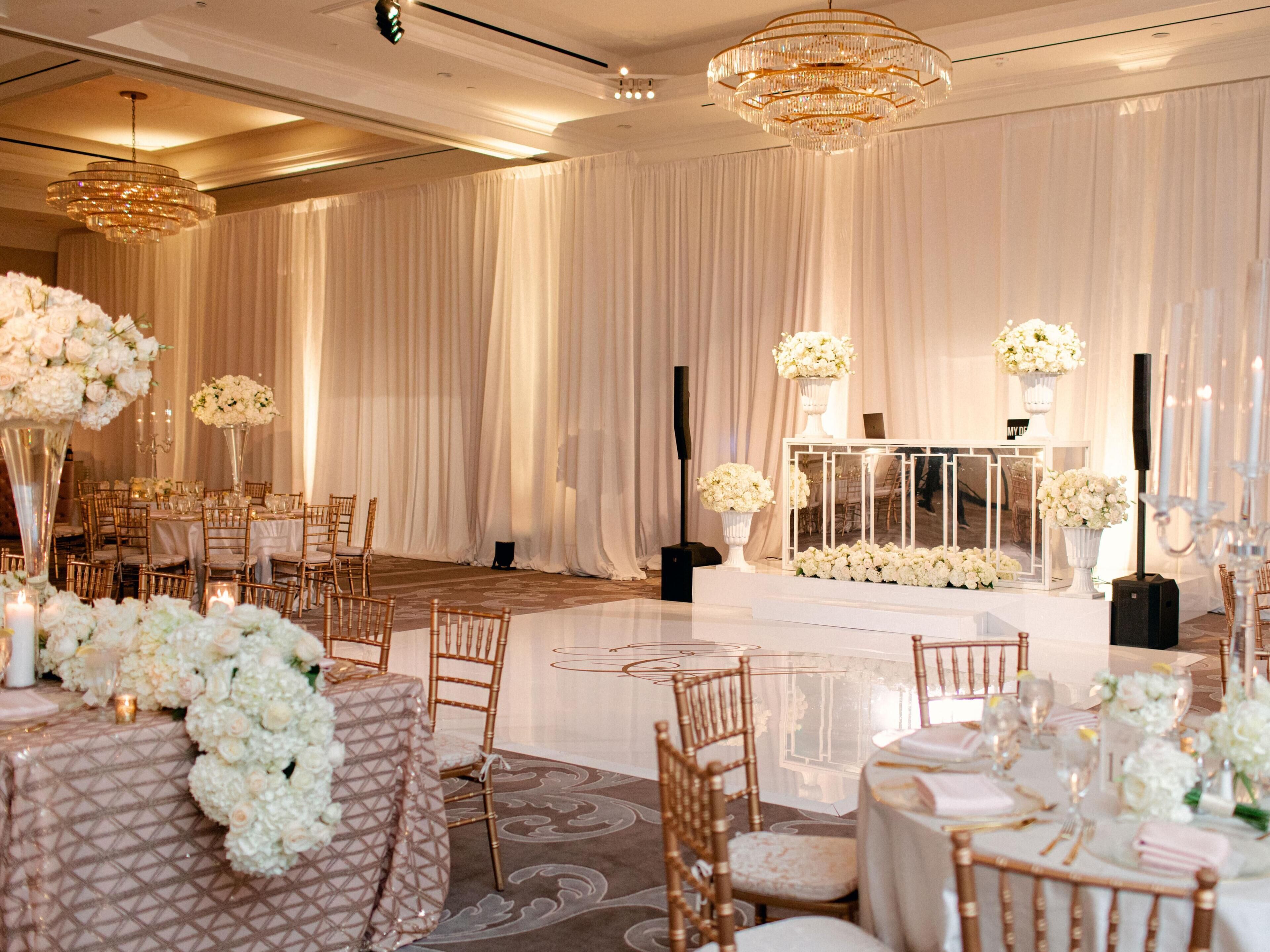 Une salle de banquet avec des tables rondes, des chaises et des centres de table floraux.