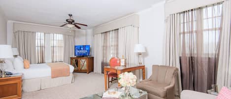 A hotel room with a bed, a sofa, a coffee table, a TV, and curtains.