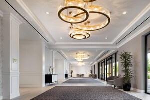 Een ruime hotel lobby met een weelderige kroonluchter, een receptiebalie en een groot raam met uitzicht.