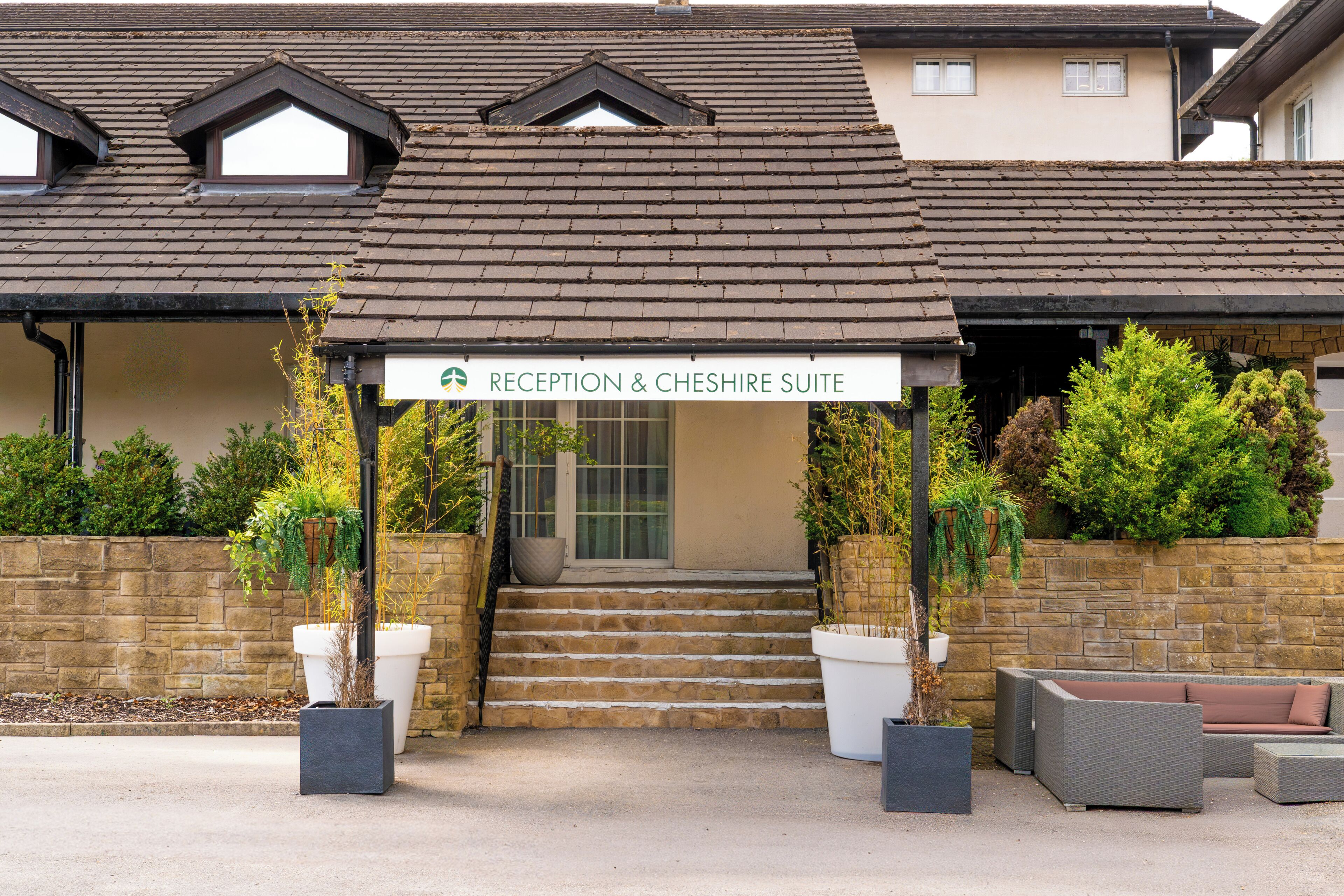 Una entrada de edificio con un letrero que dice 'RECEPTION & CHESHIRE SUITE'.