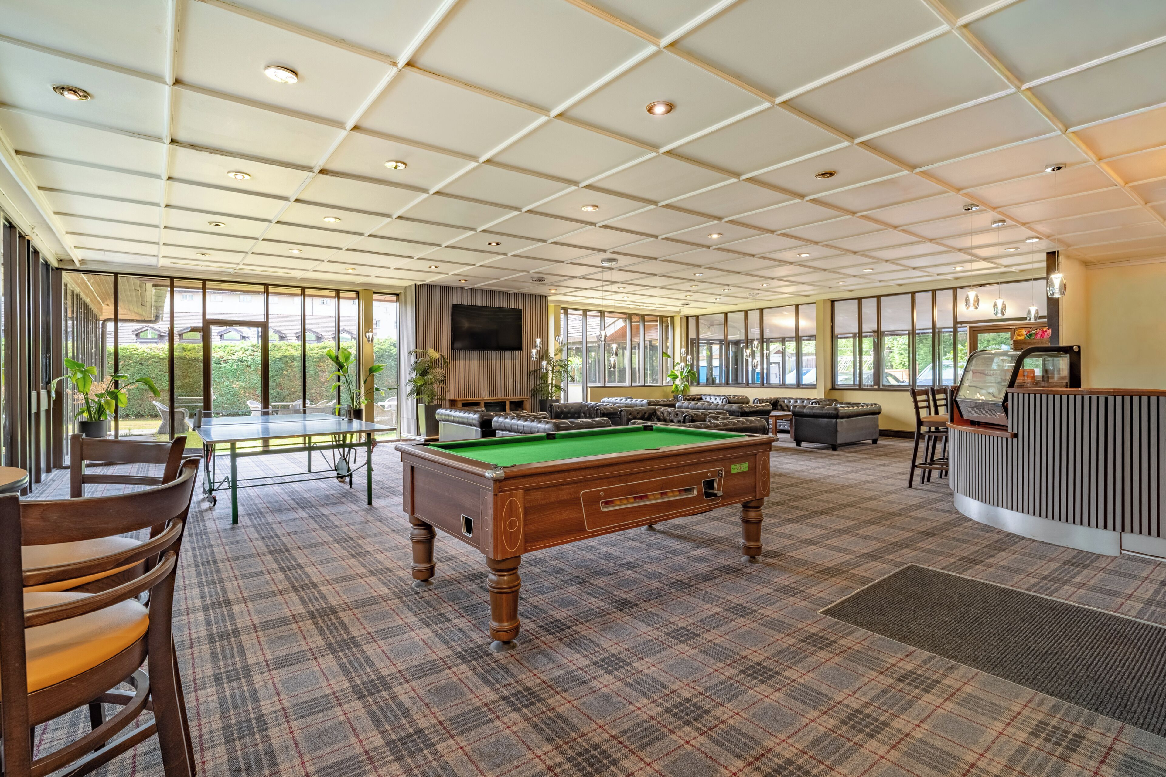 A billiards room with a pool table, seating area, and a bar.