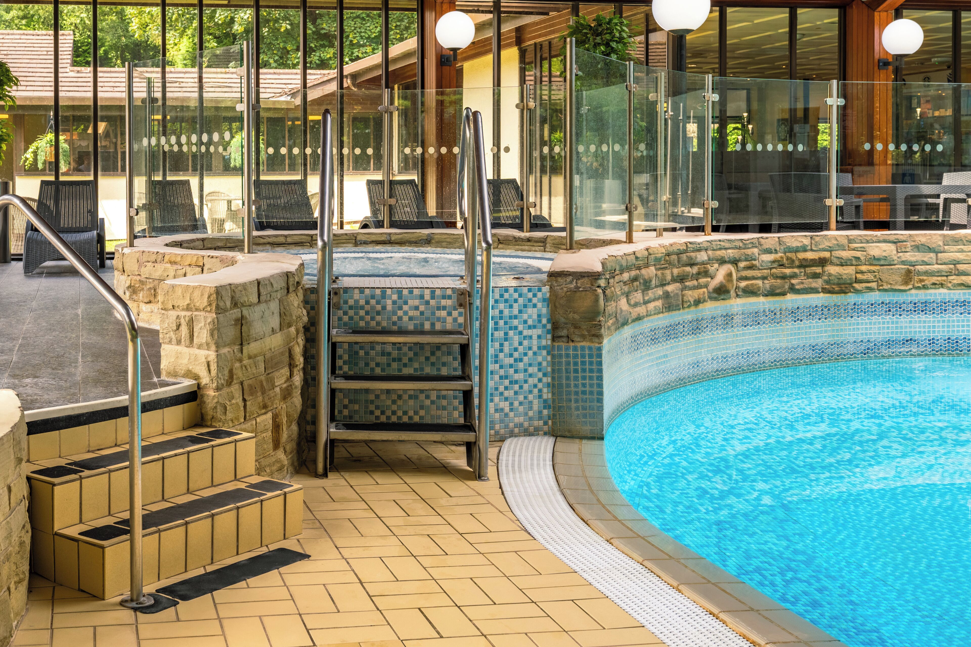 Une piscine avec un mur en pierre et des marches carrelées menant à l’intérieur.