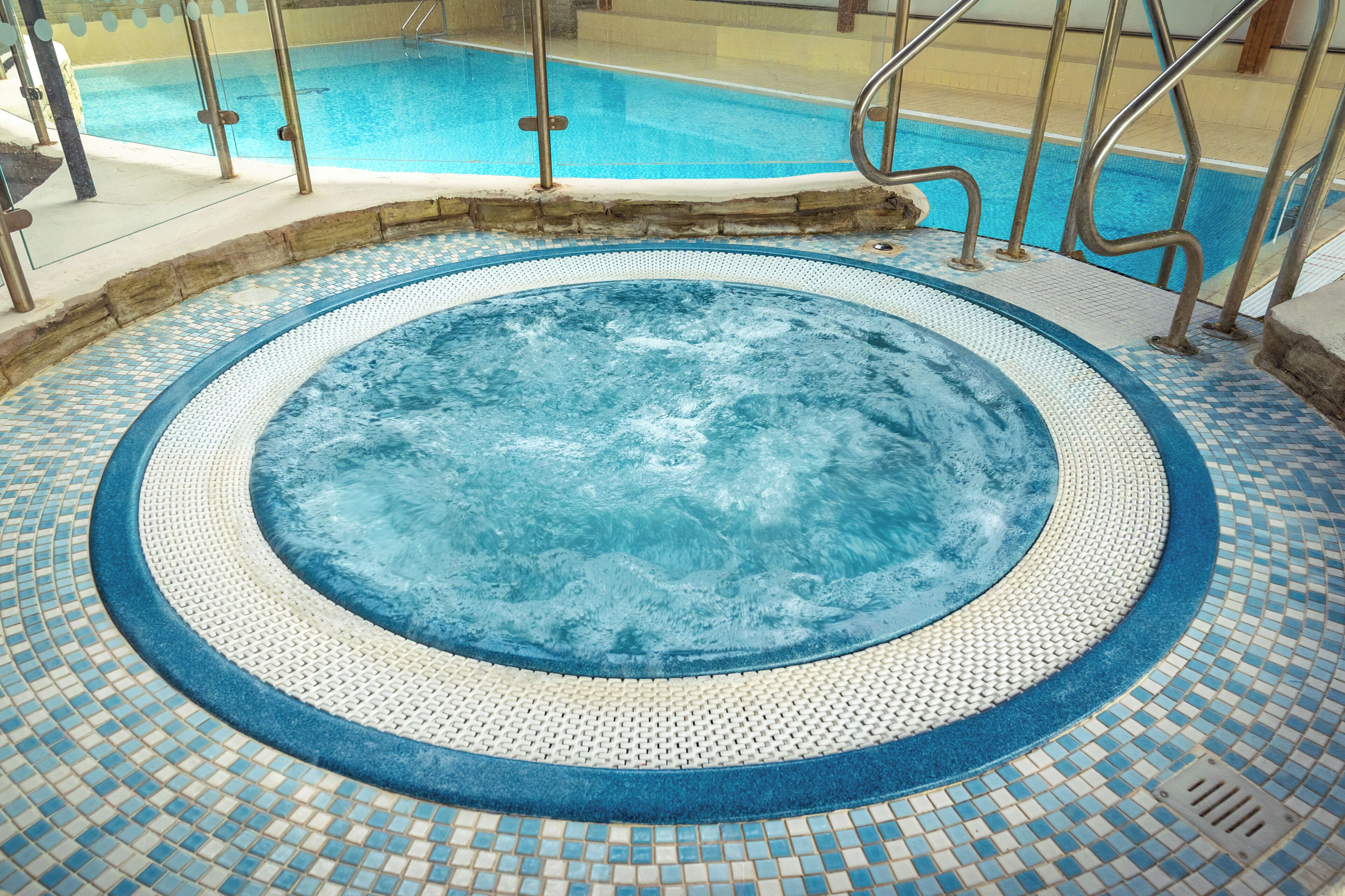 A hot tub with a tiled floor and metal railings.