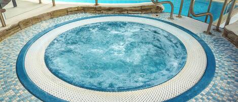A hot tub with a tiled floor and metal railings.