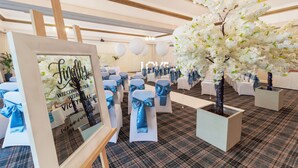 A wedding reception venue with white chairs, blue sashes, and a large white floral arrangement. - Britannia Airport Inn Manchester (Wilmslow)