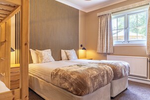 Un dormitorio con una cama grande, un panel de pared de listones de madera, una ventana con cortinas y un radiador.