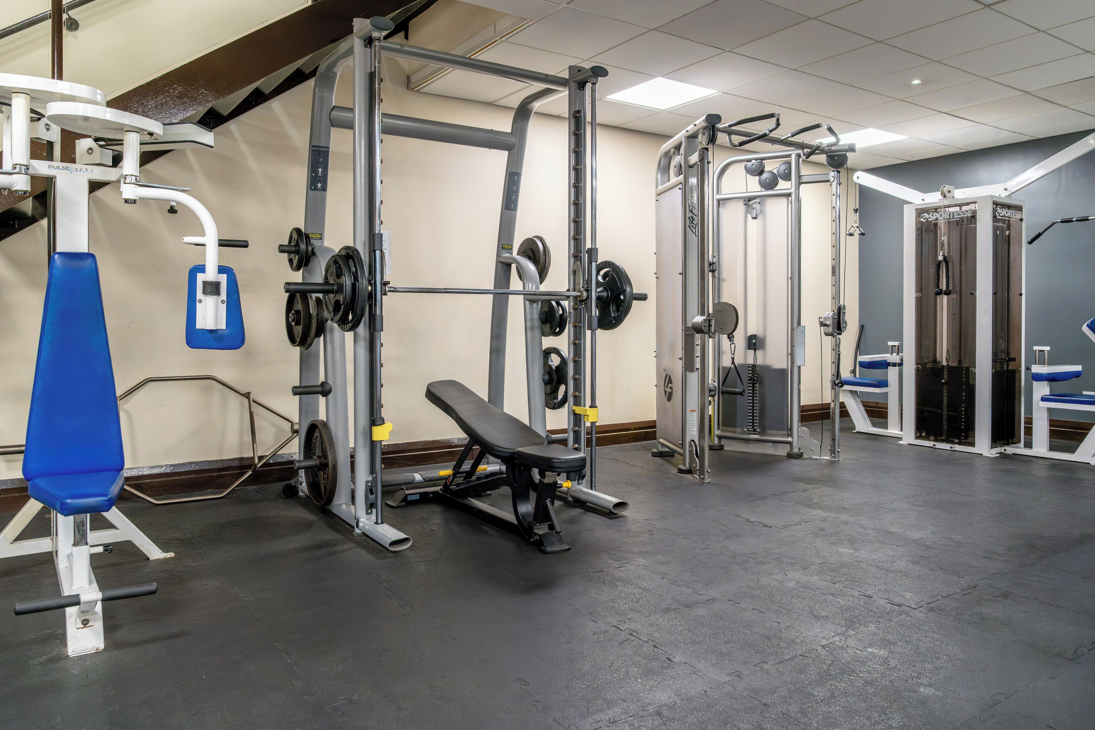 A gym with various weightlifting equipment, including a squat rack, bench press, and free weights.