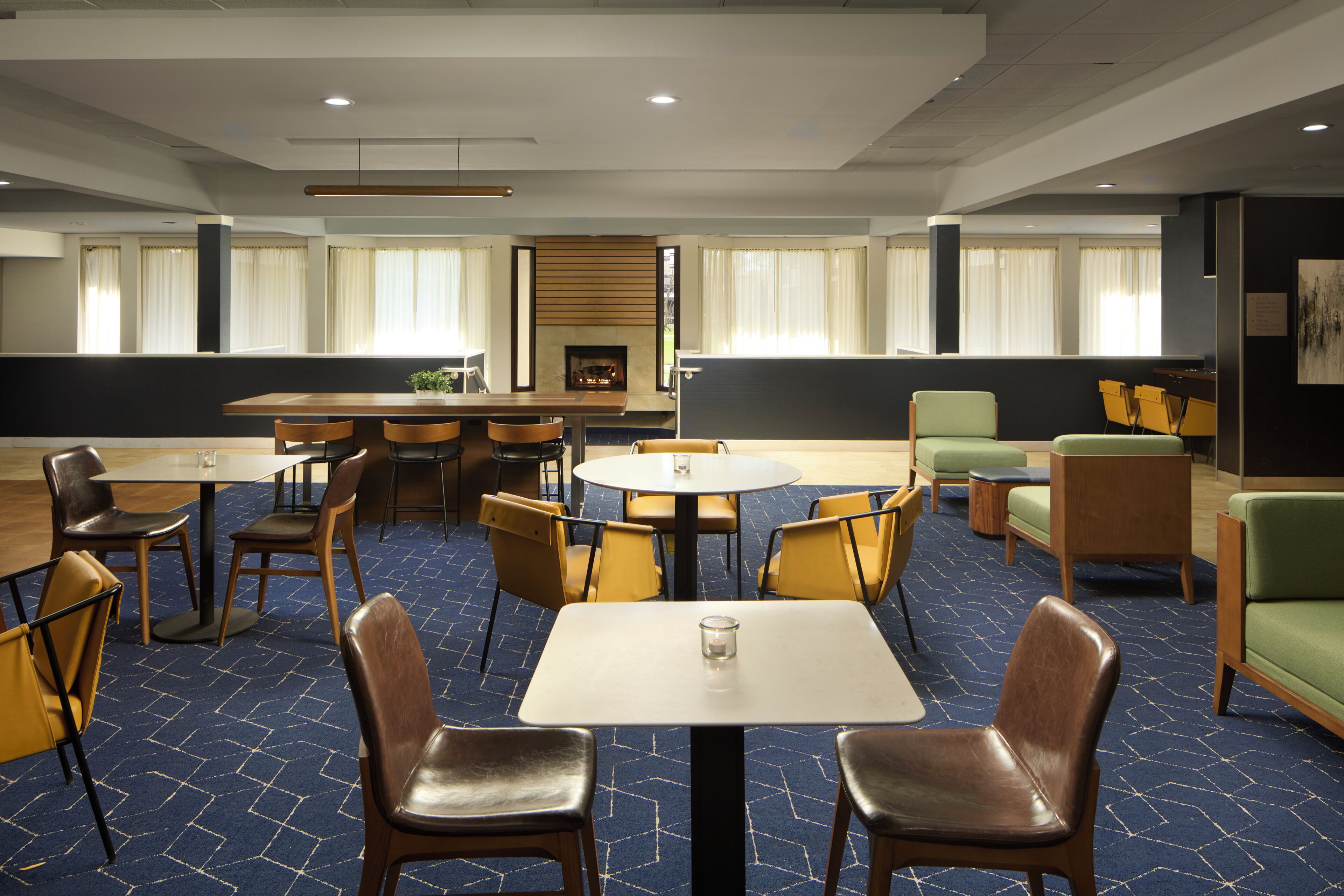 Una habitación de hotel con comedor, chimenea y zona de estar con sofás y sillones.