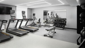 A modern gym with treadmills, weight machines, and a mirrored wall.