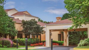 A hotel entrance with a clearway sign, surrounded by well-maintained landscaping and trees.