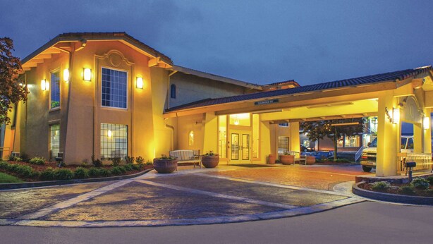 A hotel entrance with a covered driveway and a parking area. - La Quinta Inn by Wyndham Moline Airport (Moline)