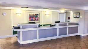 A reception desk with a clock, a framed painting, and a welcome sign. - La Quinta Inn by Wyndham Moline Airport (Moline)