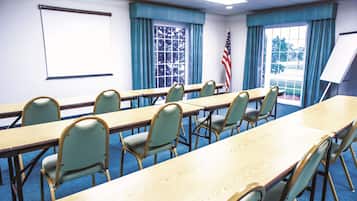 A conference room with a long table, chairs, a projector screen, and an American flag.