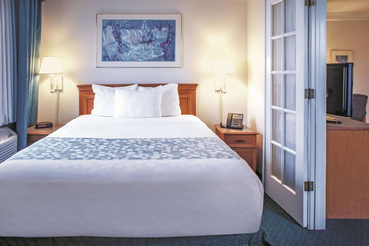 A hotel room with a large bed, two bedside tables, a desk, and a chair.