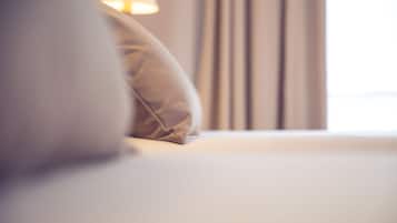 A close-up of a bed with a pillow and a lamp in the background.