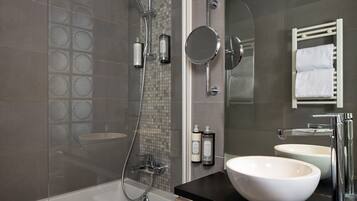 Une salle de bain moderne avec une baignoire, un grand miroir et deux lavabos.