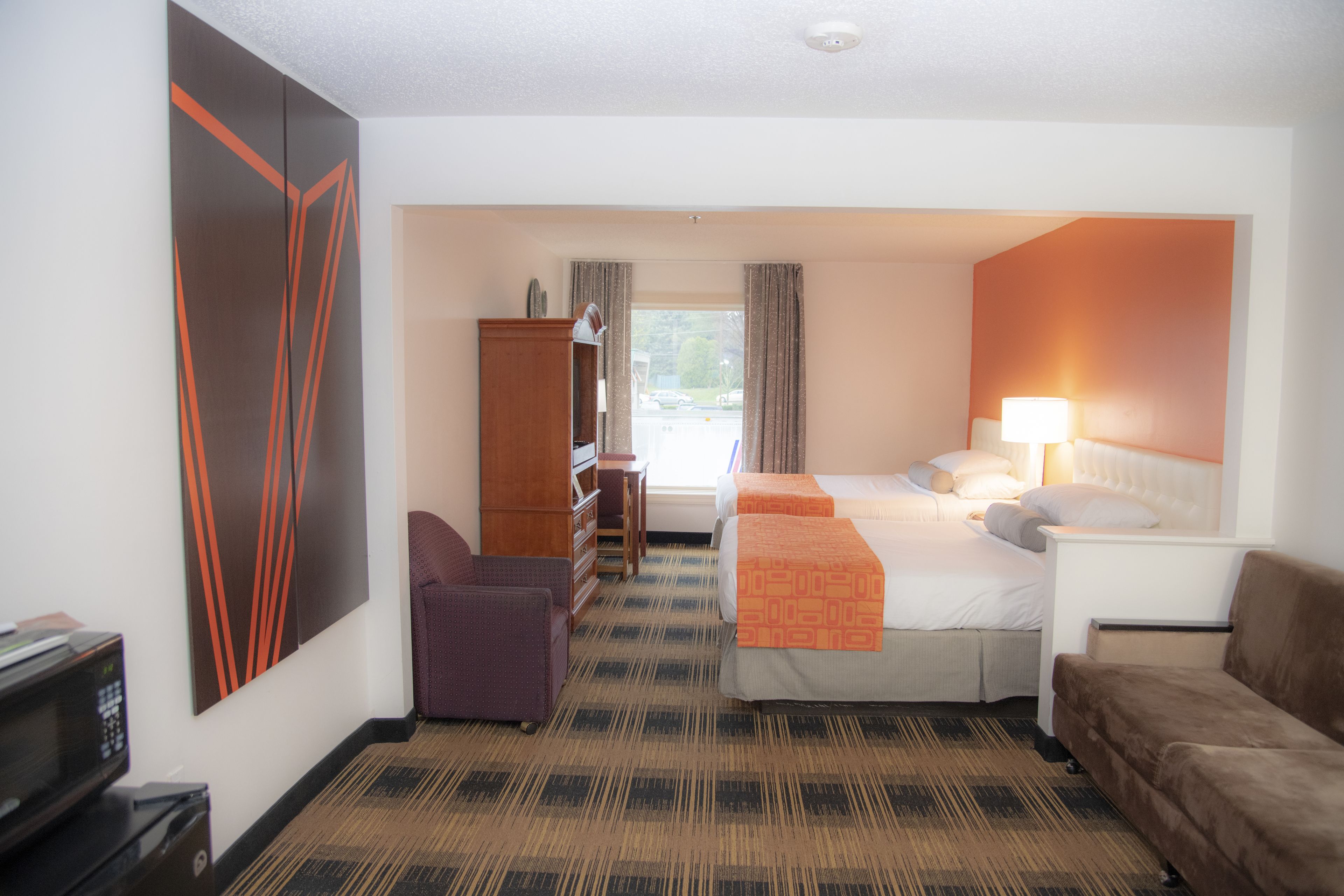 Une chambre d’hôtel comprenant un lit, un bureau, une chaise, une armoire et un téléviseur.