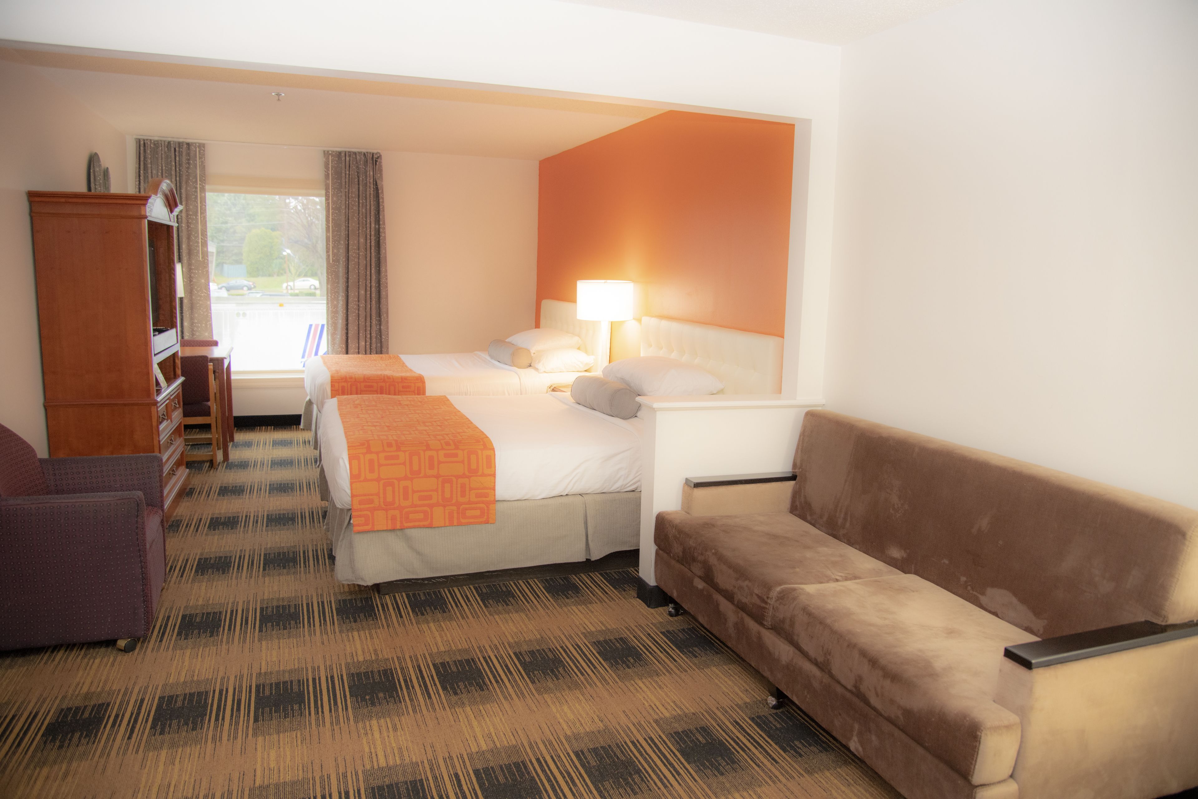 A hotel room with a bed, a sofa, a desk, and a wardrobe.