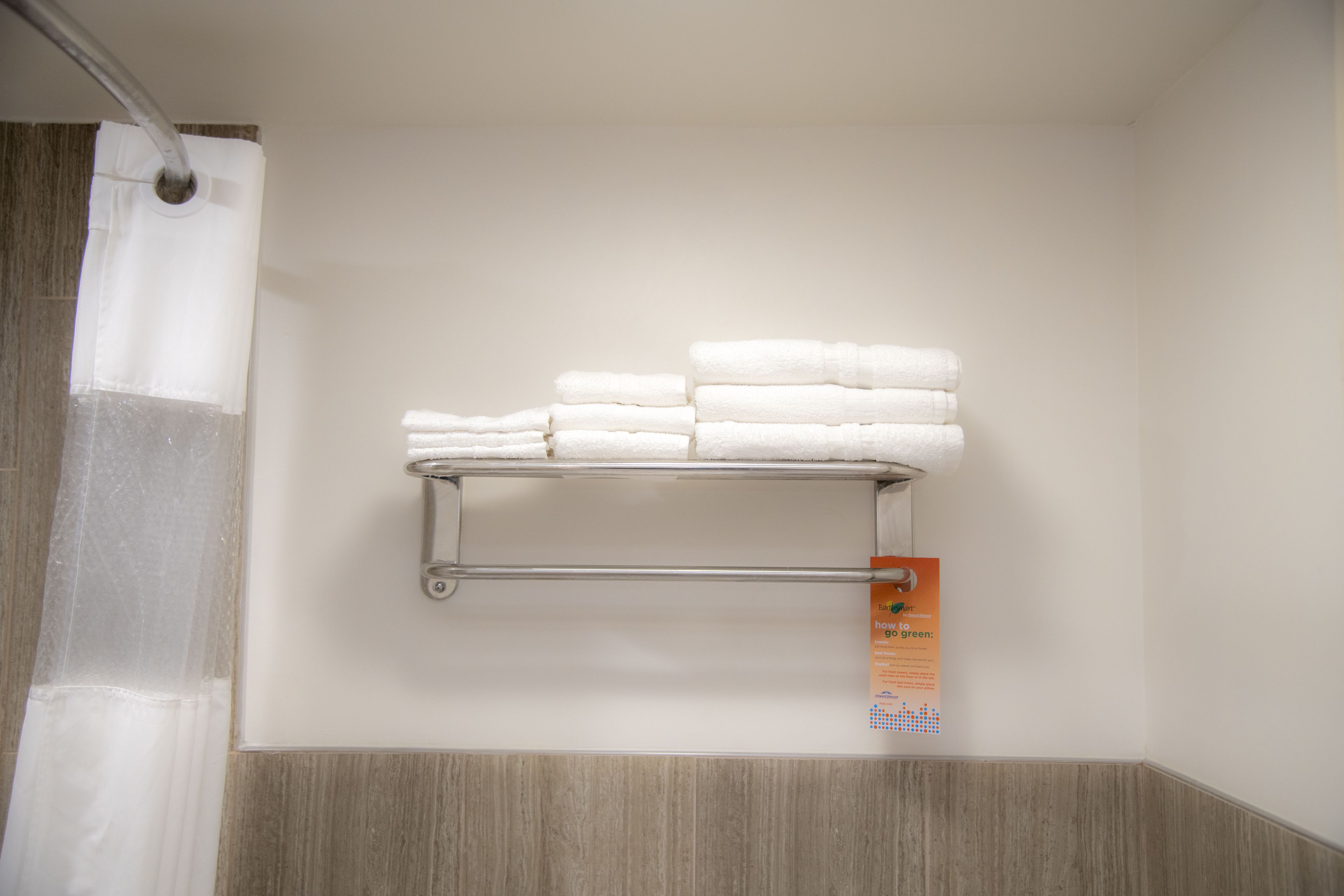 A bathroom with a towel rack holding folded towels and a shower curtain.