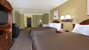 Una habitación de hotel con dos camas, televisión, escritorio y lámpara.
