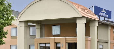 A Howard Johnson hotel with a curved roof, beige exterior, and a signboard.