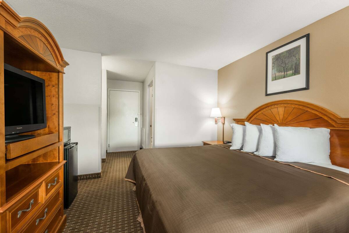 Ein Hotelzimmer mit Bett, Fernseher, Schreibtisch und Lampe.