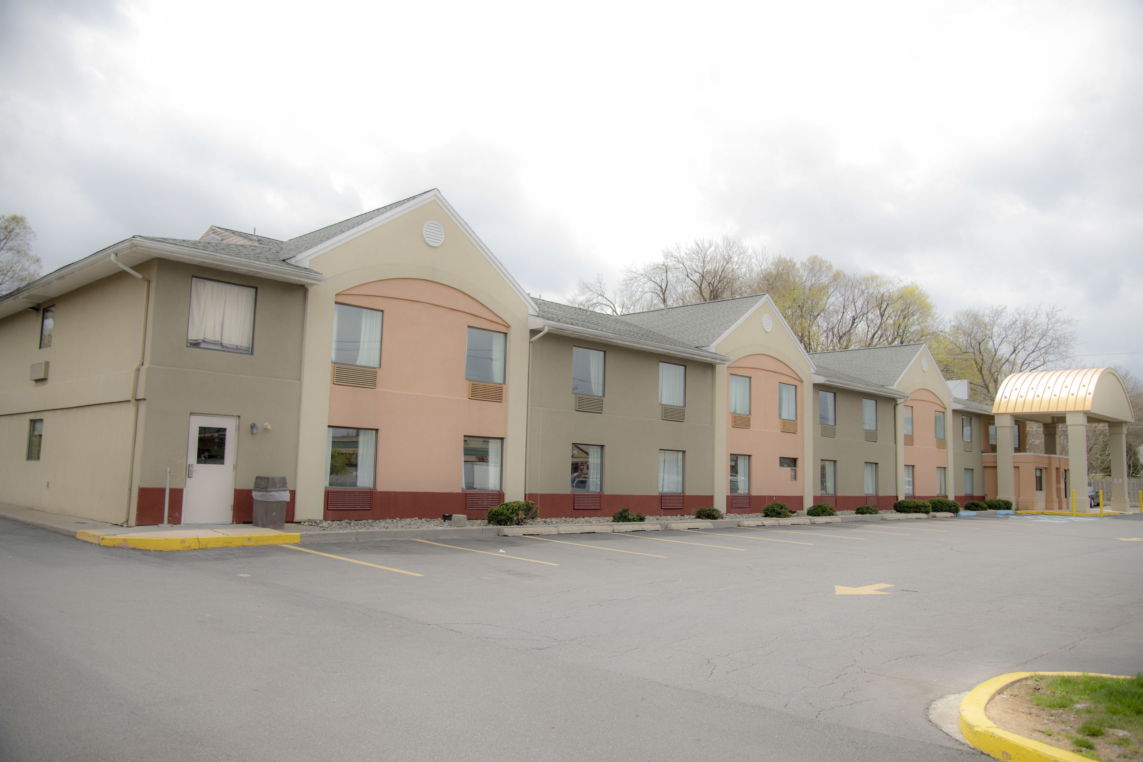 A row of hotel buildings with a parking lot in front.