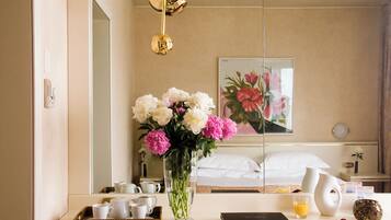 Een hotelkamer met een bed, een nachtkastje met een laptop, een bloemenvaas en een ontbijttray.