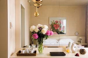 Una camera d'albergo con un letto, un comodino con un portatile, un vaso di fiori e un vassoio per la colazione.