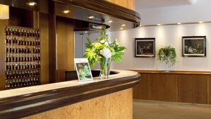 A reception area with a wooden reception desk, a wall-mounted wine cooler, and framed pictures on the wall.