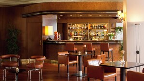 A bar area with a counter, shelves of bottles, and seating with tables and chairs.