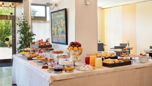 A buffet table with various food items and beverages, a painting on the wall, and a potted plant.