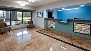A reception area with a marble floor, two armchairs, a blue wall with a reception desk, and a TV mounted on the wall. - Best Western Emporia (Emporia)