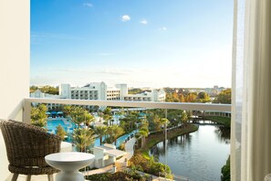 A balcony with a view of a swimming pool, a bridge, and surrounding buildings. - Hilton Orlando Buena Vista Palace - Disney Springs® Area (Lake Buena Vista)