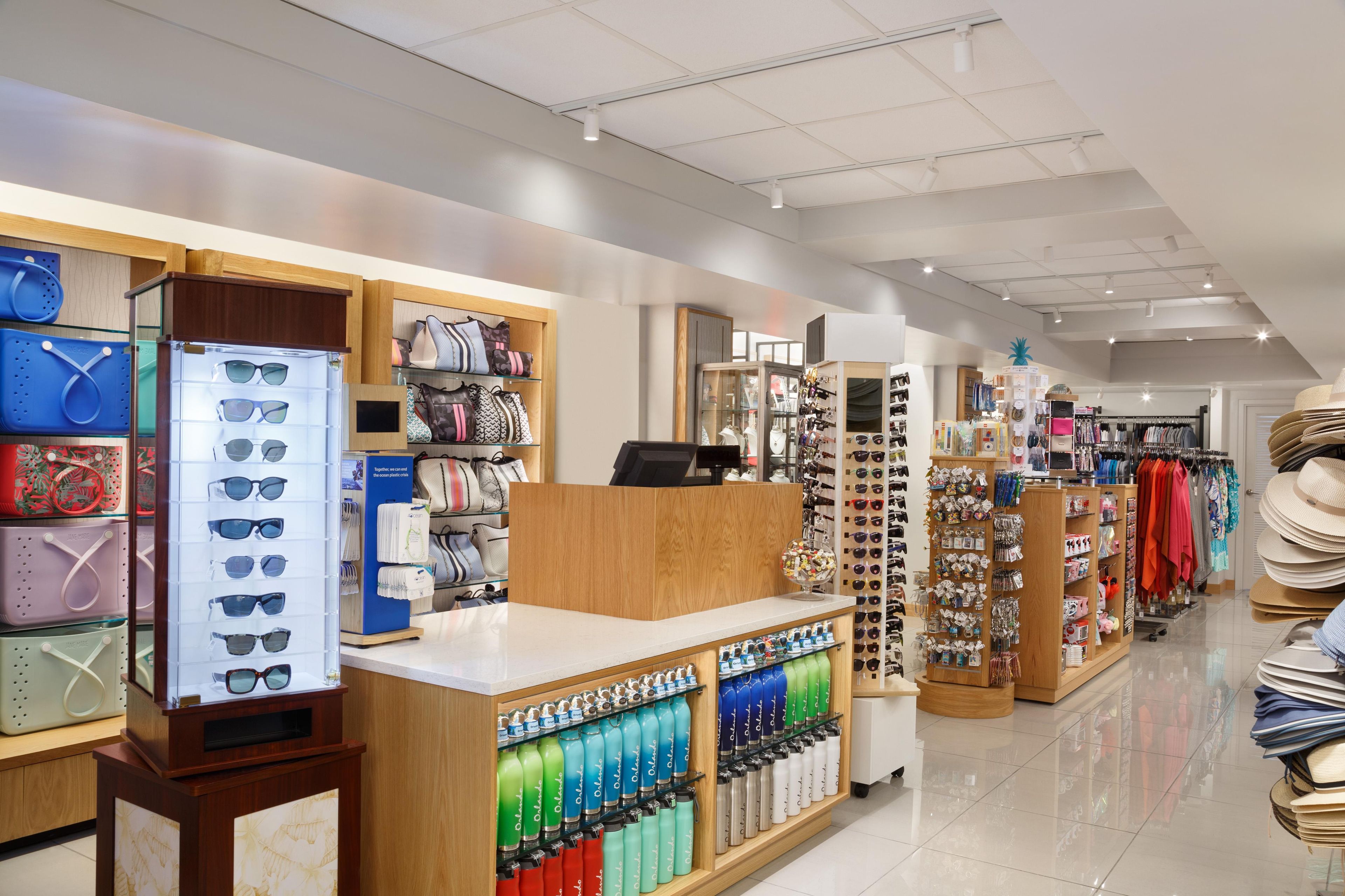 A retail store with various items on display including sunglasses, bags, hats, and water bottles.