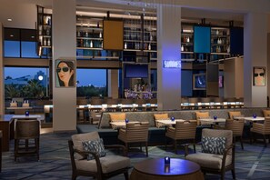 A modern bar area with multiple seating options, including sofas and chairs, and a variety of bottles displayed on shelves. - Hilton Orlando Buena Vista Palace - Disney Springs® Area (Lake Buena Vista)