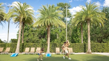 A well-maintained outdoor area with palm trees, lounge chairs, and a clear sky.