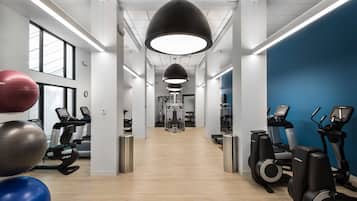 A gym with exercise equipment, large windows, and a blue accent wall.