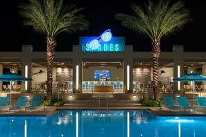 A hotel with a pool, palm trees, and a neon sign. - Hilton Orlando Buena Vista Palace - Disney Springs® Area (Lake Buena Vista)