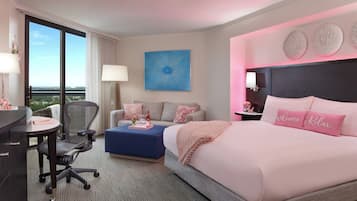 Una habitación de hotel con una cama grande, un escritorio, una silla, un sofá y vistas al exterior.