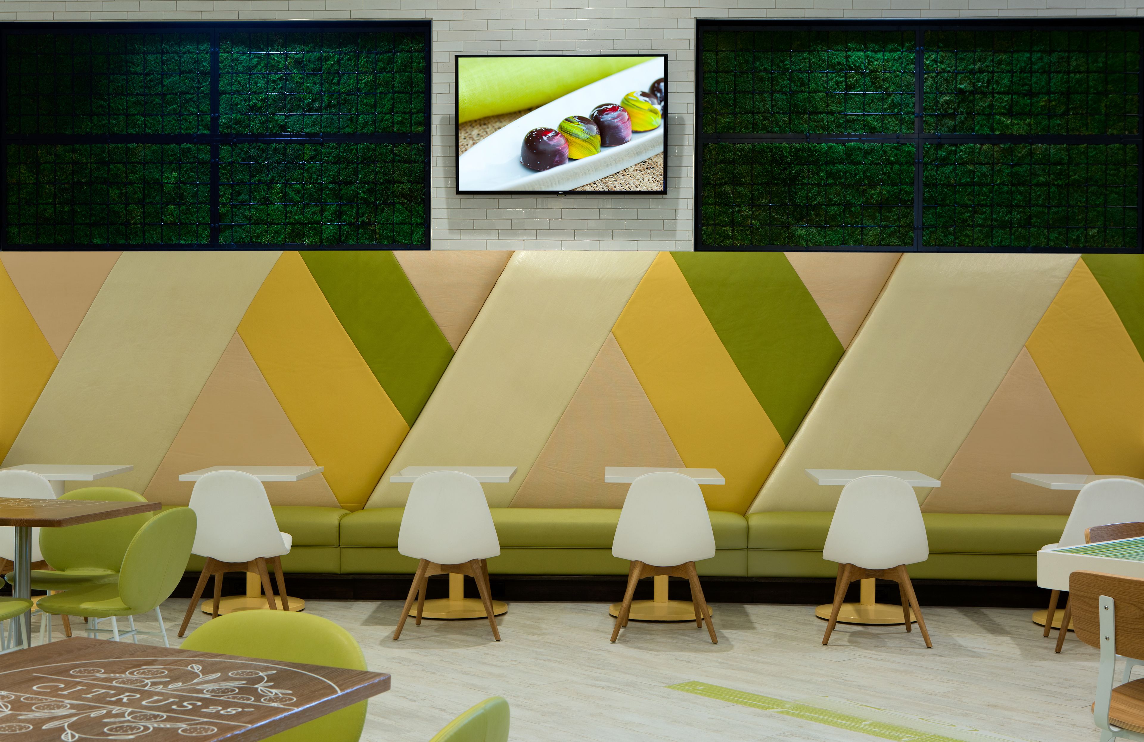 Ein modernes Interieur mit einem grünen Sofa, weißen Tischen und Stühlen.