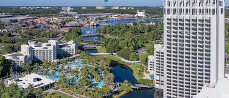 Un resort con varias piscinas, una extensa masa de agua y un edificio de gran altura.